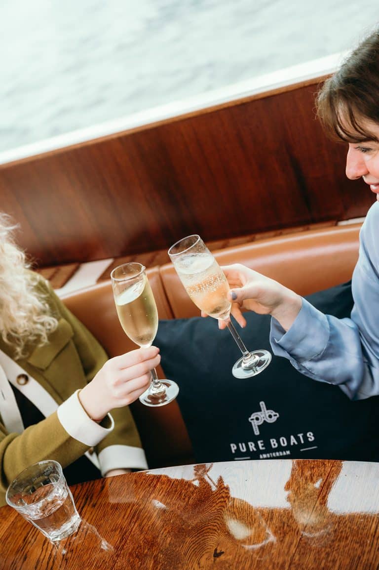 Guests clinking glasses of champagne aboard canal cruise boat in Amsterdam